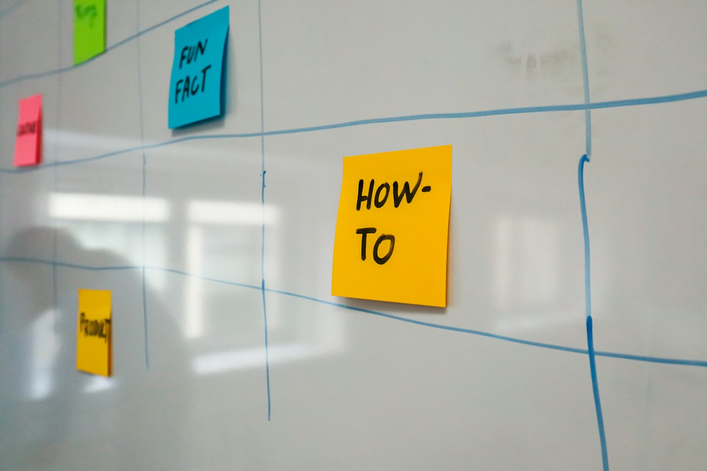 Whiteboard with colorful sticky notes and blue grid lines for brainstorming.
